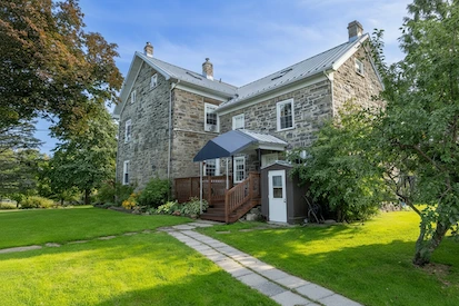 Historic stone building with wooden deck and landscaped grounds